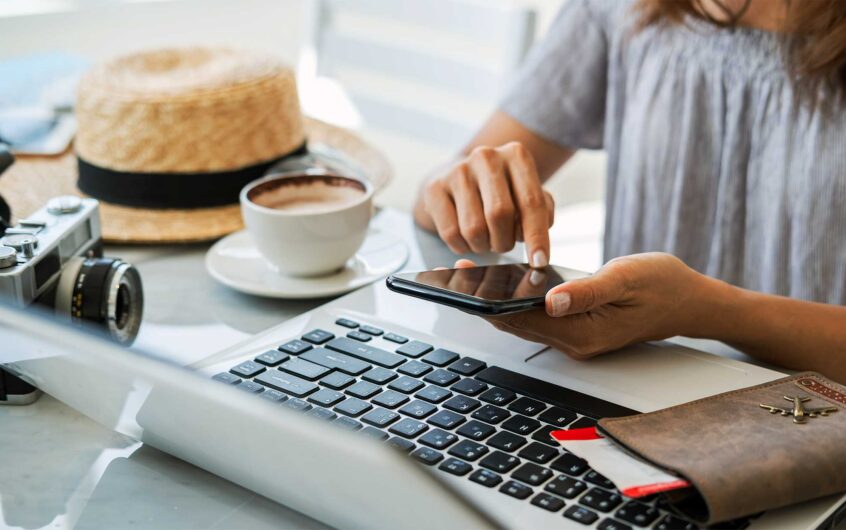 Traveler planning a trip on mobile device and laptop, representing search optimization for tourism and AI-powered travel planning